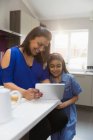 Мати і дочка використовують цифровий планшет на кухні — стокове фото