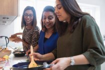 Happy Indian women cooking food in kitchen — Stock Photo