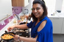 Portrait femme indienne heureuse cuisiner la nourriture à la cuisinière dans la cuisine — Photo de stock