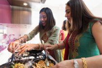 Индийские женщины в сари готовят еду на плите на кухне — стоковое фото