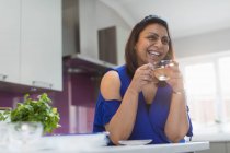 Щаслива жінка п'є чай на кухні — стокове фото