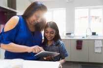 Мать и дочь с помощью цифрового планшета на кухне — стоковое фото