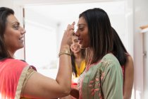Indian woman placing bind on forehead of sister — Stock Photo