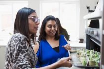 Indian women placing kebabs in oven in kitchen — Stock Photo