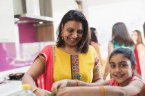 Mère et fille indiennes dans les saris cuisine des aliments dans la cuisine — Photo de stock