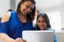 Madre e hija feliz usando tableta digital - foto de stock