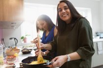 Portrait happy Indian woman cooking food at stove in kitchen — Stock Photo