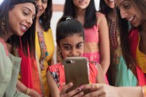 Mulheres indianas e meninas em saris e bindis usando telefone inteligente — Fotografia de Stock