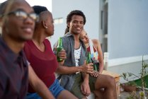 Retrato confiado joven bebiendo cerveza con amigos en el patio - foto de stock
