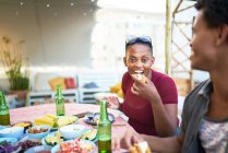 Portrait happy young woman eating taco at patio table — Stock Photo