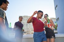 Безтурботні молоді друзі танцюють і п'ють пиво на міському даху — стокове фото