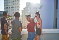 Jóvenes amigos bailando y bebiendo cerveza en el soleado tejado urbano - foto de stock