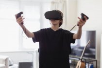 Menino jogando jogo de vídeo com óculos VRS na sala de estar — Fotografia de Stock