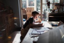 Мальчик делает уроки за обеденным столом — стоковое фото
