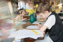 Хлопчик робить домашнє завдання за обіднім столом — стокове фото