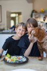 Retrato irmãos com cão comendo na mesa de jantar — Fotografia de Stock