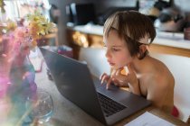 Curioso ragazzo homeschooling al computer portatile in cucina — Foto stock