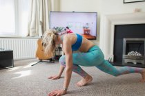 Femme pratiquant le yoga en ligne dans le salon — Photo de stock