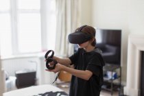 Menino jogando jogo de vídeo com óculos VRS na sala de estar — Fotografia de Stock