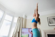 Woman practicing yoga online in living room — Stock Photo