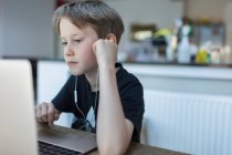 Konzentrierter Junge mit Kopfhörern am Laptop — Stockfoto