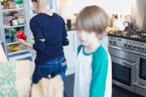 Mãe e filho descarregar mantimentos na cozinha — Fotografia de Stock