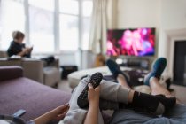 POV family with remote control watching TV in living room — Stock Photo