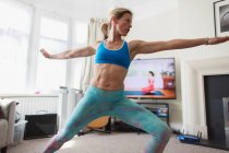 Жінка практикує онлайн йогу у вітальні — стокове фото