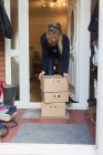 Mujer recuperando cajas de productos de la entrada delantera - foto de stock