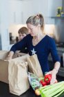 Mother and son unloading fresh produce in kitchen — Stock Photo