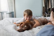 Симпатичний хлопчик надувається з собакою на ліжку — стокове фото