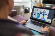 Woman video chatting with doctors at laptop from home — Stock Photo