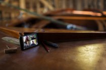 Colegas video chat en la pantalla del teléfono inteligente en barco de madera - foto de stock