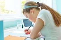 Сосредоточенная девушка делает уроки за столом — стоковое фото
