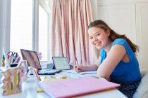 Portrait confident girl homeschooling at desk in bedroom — Stock Photo