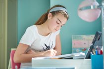 Дівчина робить домашнє завдання за столом у спальні — стокове фото