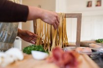 Жінка робить свіжі домашні макарони на кухні — стокове фото