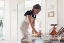 Adolescente pétrissant pâte à pain dans la cuisine — Photo de stock