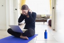 Ragazza adolescente che pratica yoga online con il computer portatile — Foto stock