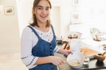 Portrait confiant adolescent fille cuisson dans la cuisine — Photo de stock