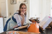 Portrait happy teenage girl baking in kitchen — Stock Photo