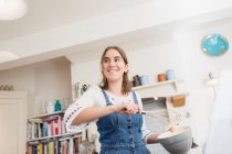 Menina adolescente sorridente com whisk e boliche assando na cozinha — Fotografia de Stock
