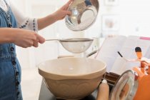 Teenagermädchen sieben Mehl zum Backen in Küche — Stockfoto
