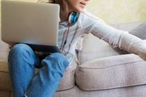 Teenage girl with laptop on sofa — Stock Photo