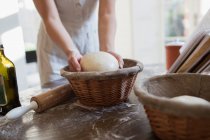 Woman placing dough into proofing basket in kitchen — Stock Photo