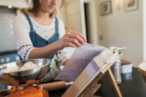 Adolescente com livro de receitas assar na cozinha — Fotografia de Stock