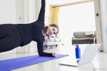 Adolescente pratiquant le yoga en ligne à l'ordinateur portable à la maison — Photo de stock
