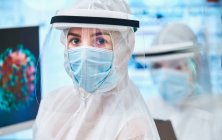 Уверенная в себе женщина-ученый в чистом костюме, изучающая коронавирус — стоковое фото
