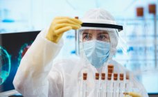 Женщина-ученый в чистом костюме исследует коронавирусную вакцину — стоковое фото