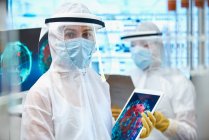 Женщина-ученый в чистом костюме, исследующая коронавирус — стоковое фото